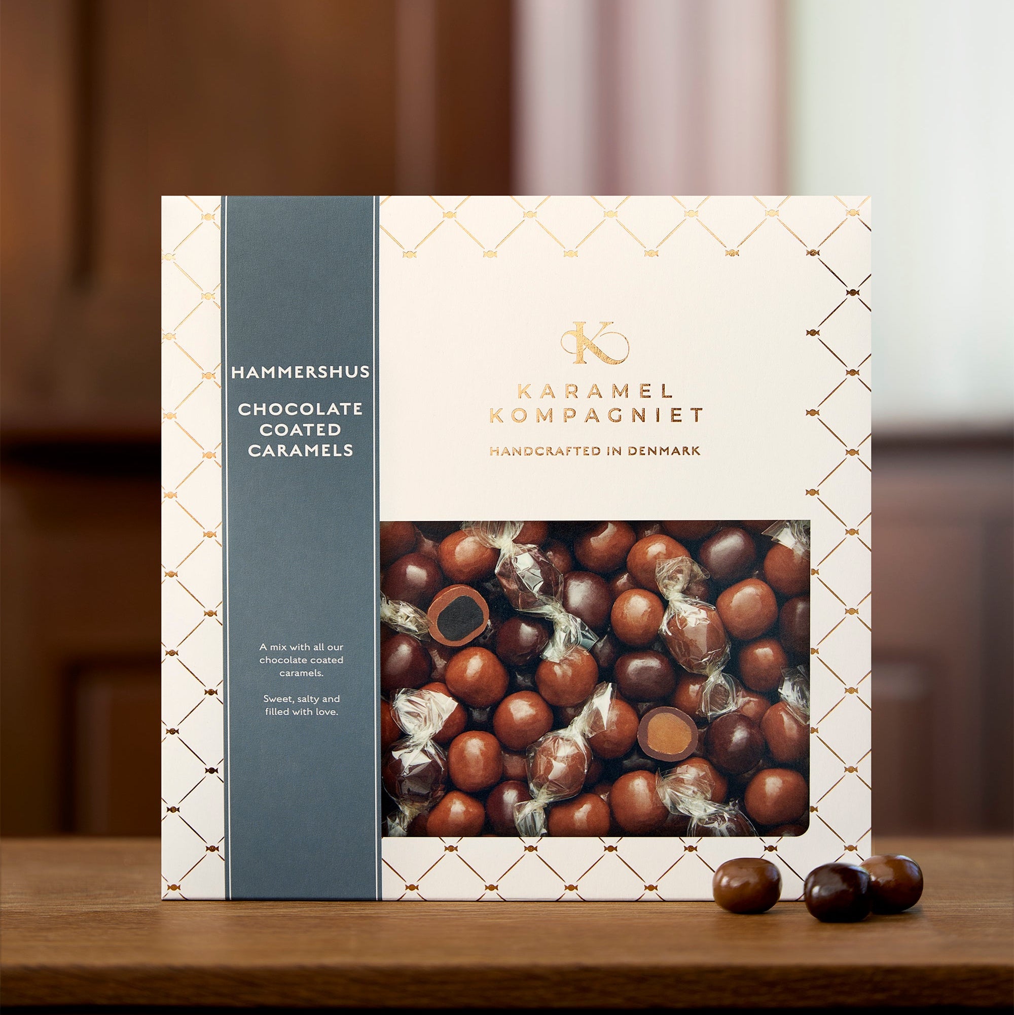 Hammershus – Chokoladeovertrukne Karamel Kugler i flere varianter i Q3-æske oprejst på et kobber bord