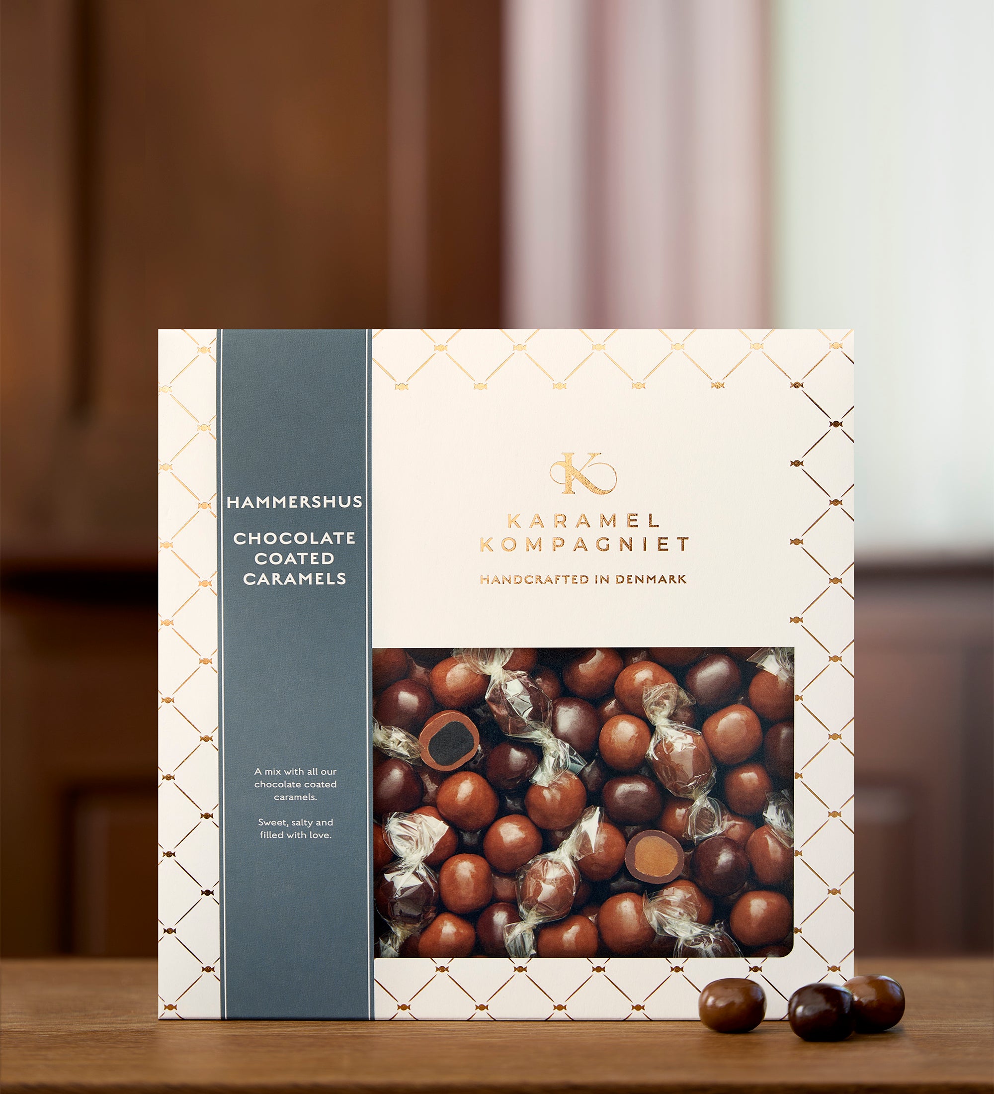 Hammershus – Chokoladeovertrukne Karamel Kugler i flere varianter i Q3-æske oprejst på et kobber bord