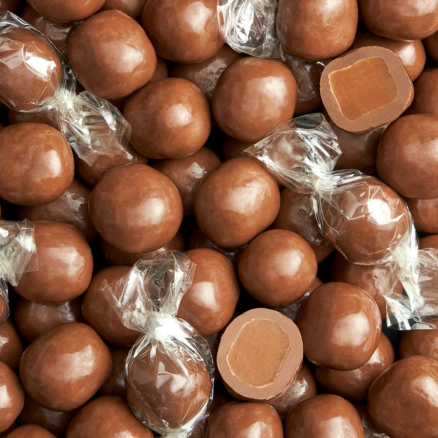Nærbillede af håndlavede flødekarameller overtrukket med lys chokolade – blød karamelkerne synlig på tværsnit