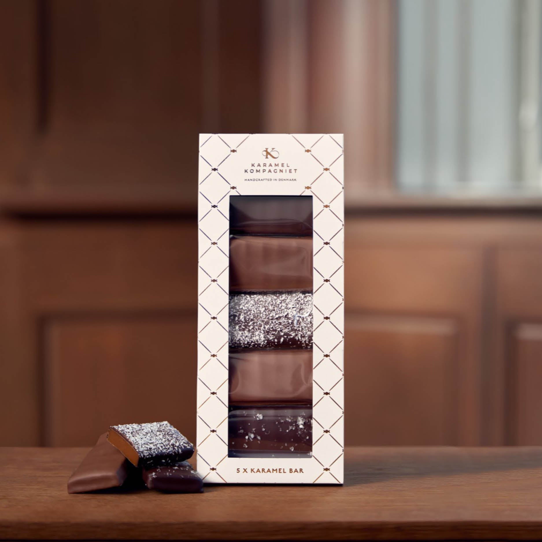 Karamel Bar Gaveæske 5 stk. fra Karamel Kompagniet på træbord – premium karamelgave med fem varianter af chokoladeovertrukne karamelbarer