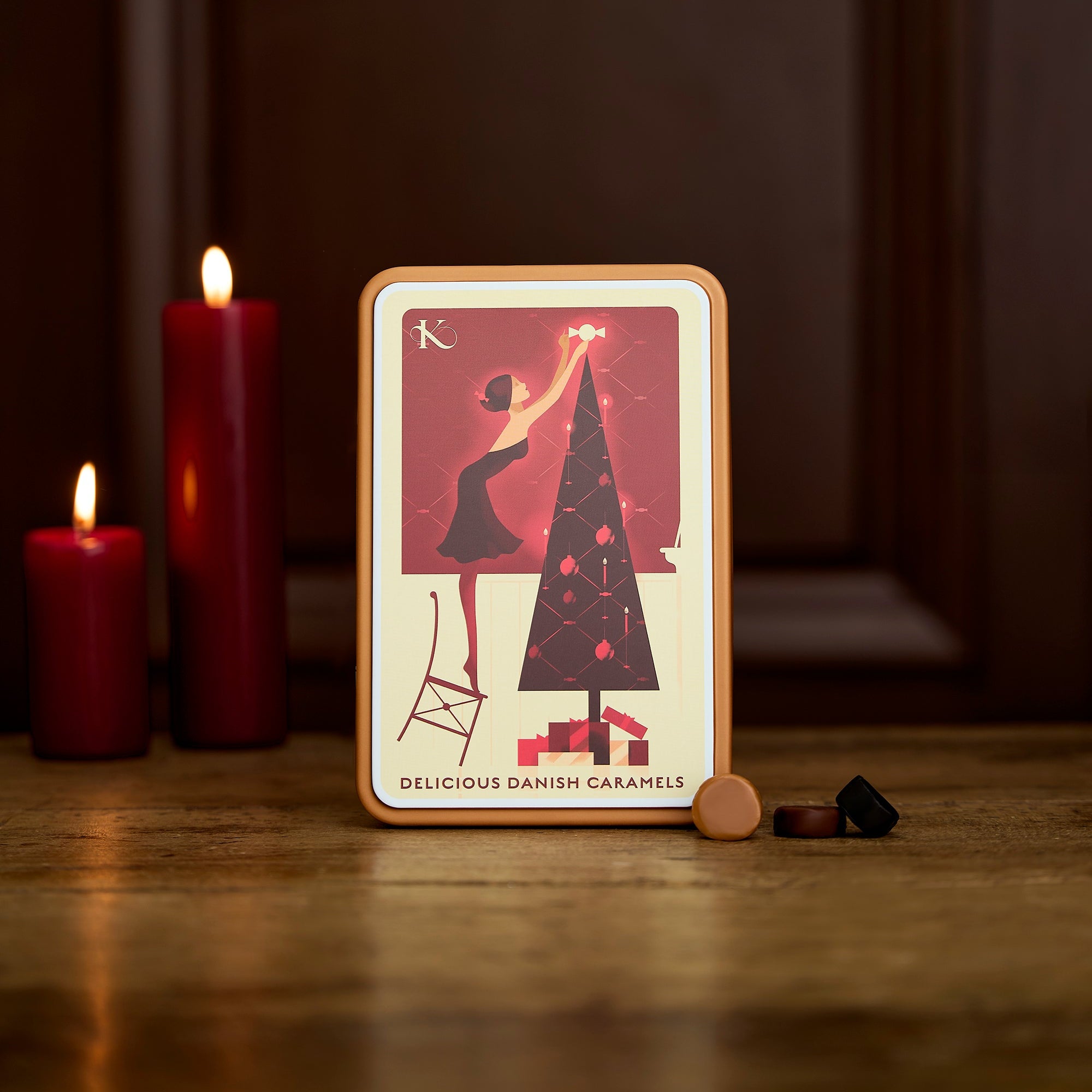 Juledag julekarameller dåse med illustration af kvinde. der sætter en karamel som stjernen på juletræet - dåse på bord