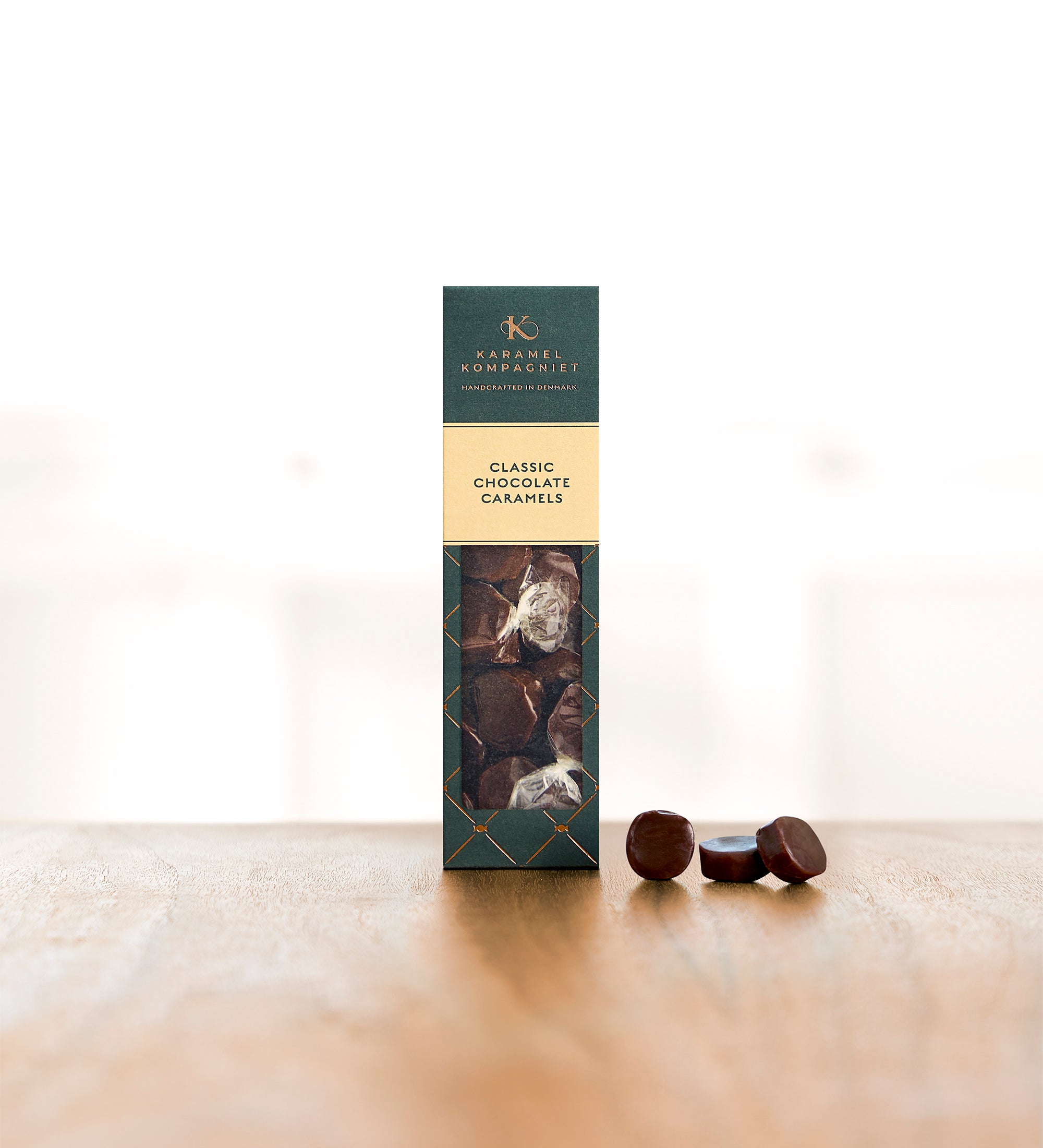 Chokoladekarameller i oprejst æske med tre karameller ved siden af