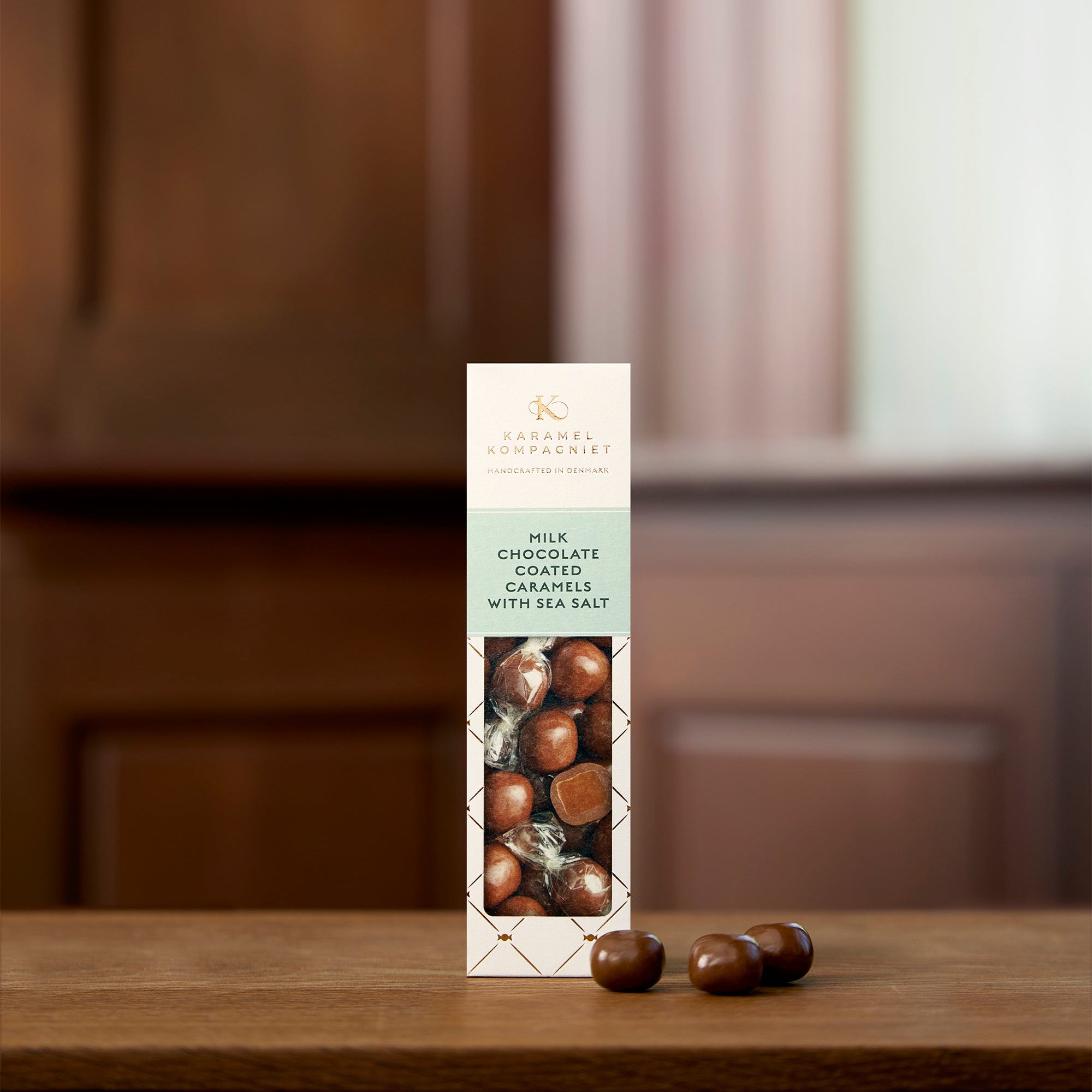 Milk Chocolate Coated Caramels with Sea Salt i hvid Elegance-æske fra Karamel Kompagniet der står på et bord – håndlavede chokoladekarameller fra Bornholm

